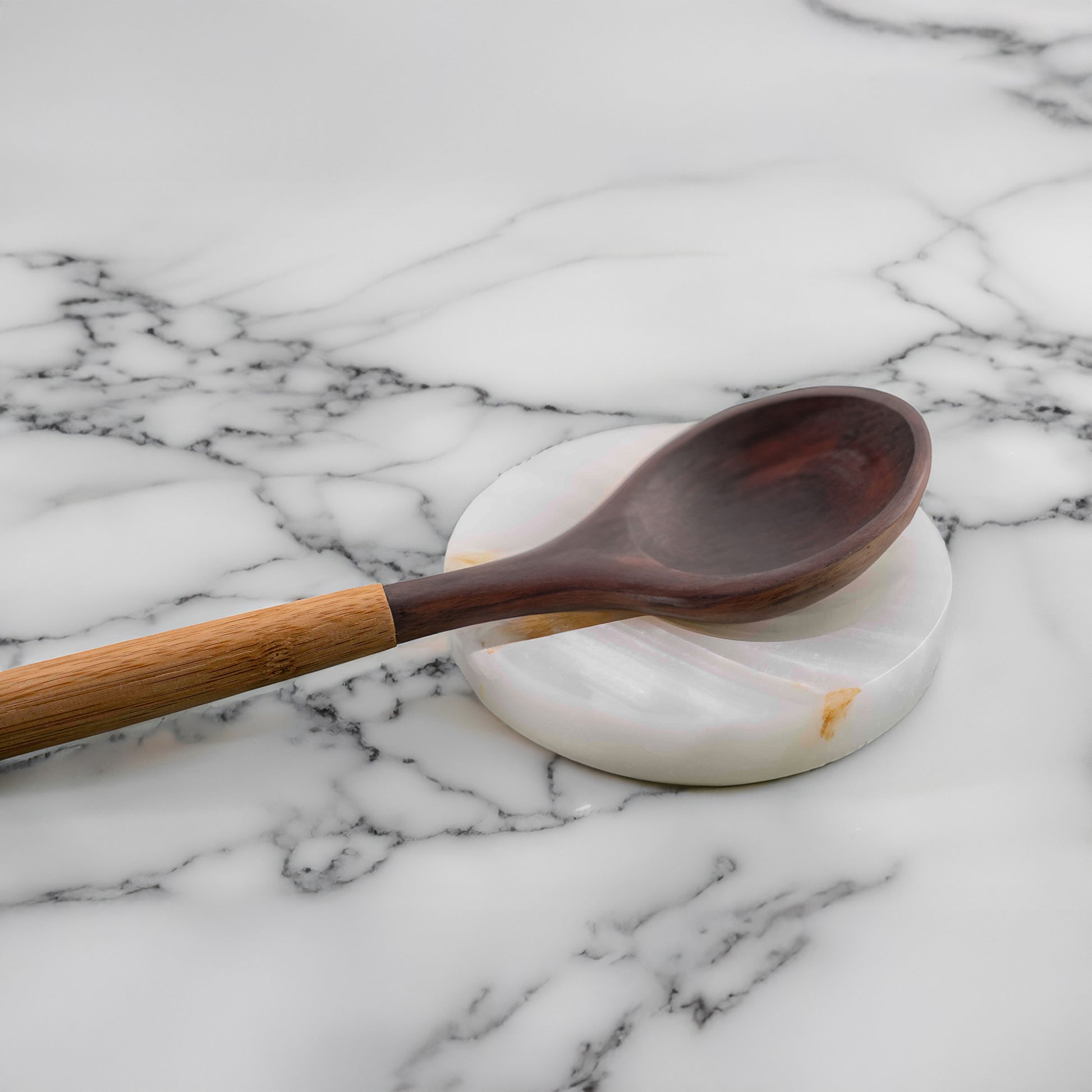 Onyx spoon rest holding a wooden spoon on a marble countertop