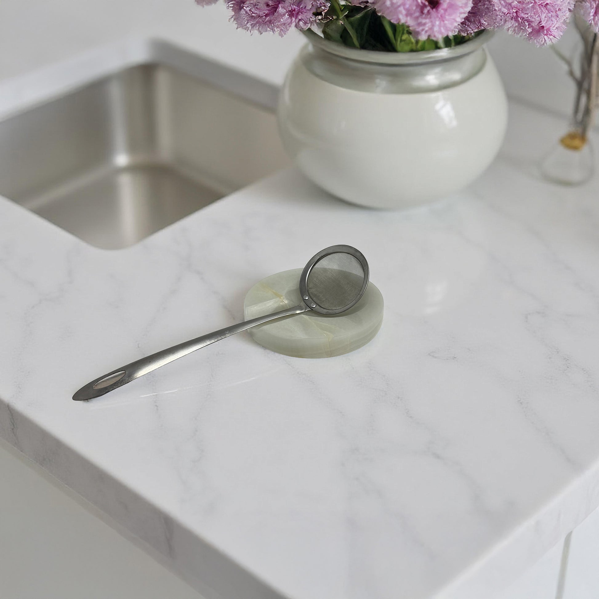 Onyx spoon rest with strainer near a flower vase on a kitchen counter