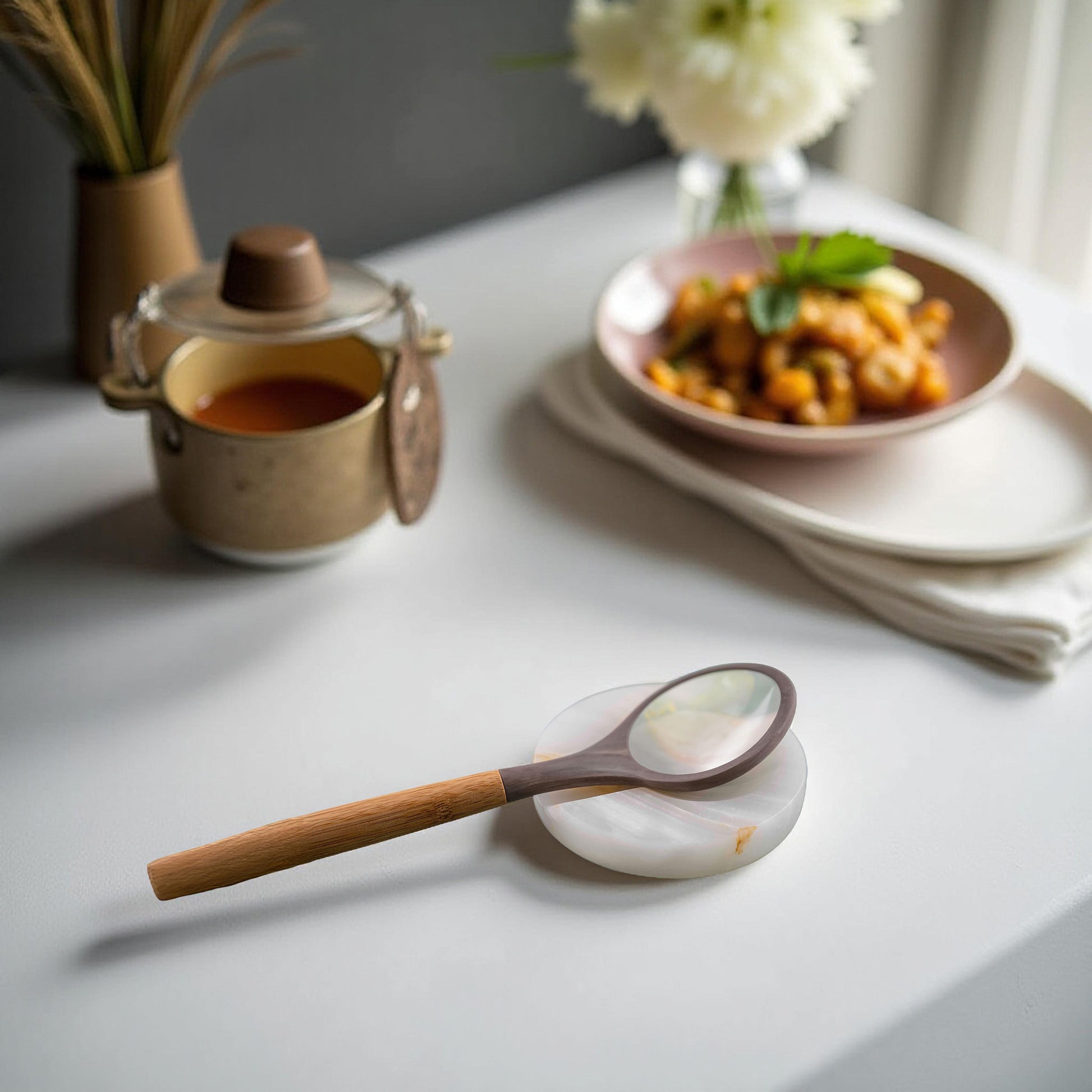 Onyx spoon rest holding a spoon next to soup pot and plate of food